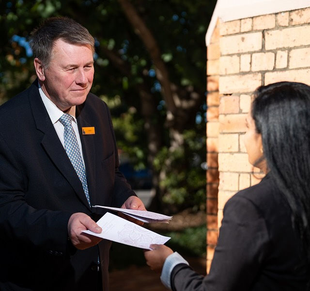 Allan Drew funeral director handing a service order to a woman
