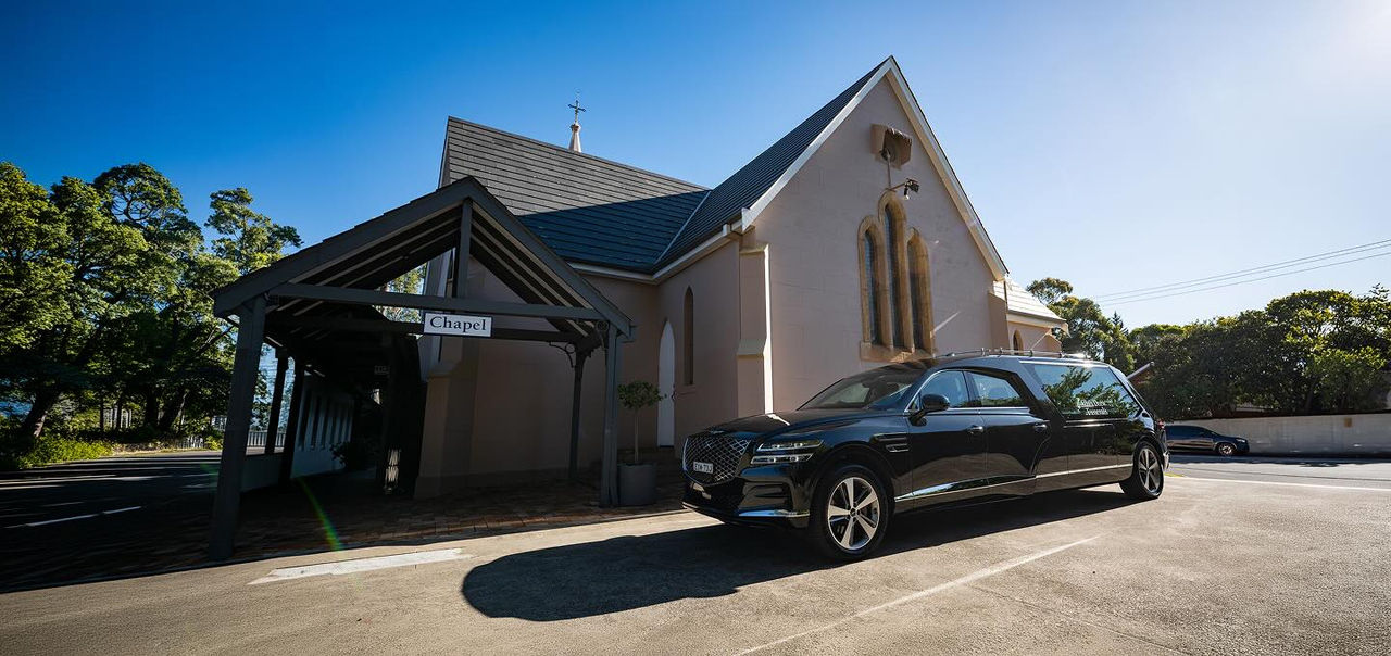 hearse parked in front of a chapel